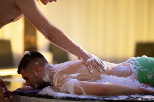 Back Massage with Foam. Therapist applies soap foam with htheir ands on patients back during traditional bath ritual