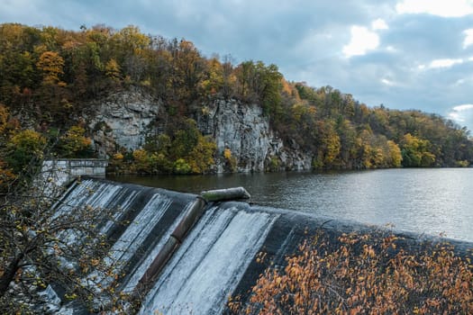 A picturesque view of a waterfall spilling into a serene lake surrounded by colorful autumn foliage.