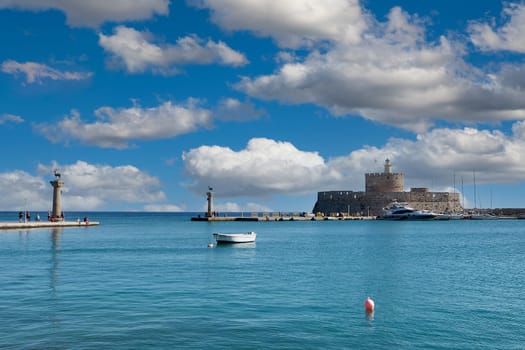 Rodas.Greece - june 04, 2025: Breathtaking panorama of Mandraki Harbour, showcasing the historic Fort of Saint Nicholas, lighthouses, and various boats under a dynamic cloudy sky.