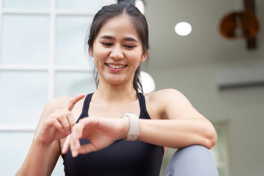 A young woman examines her smartwatch in a peaceful outdoor setting, highlighting fitness and wellness.