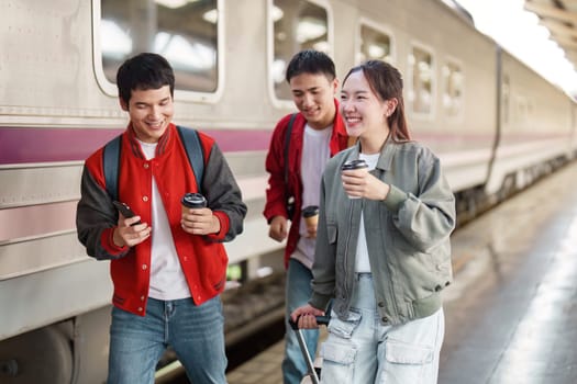 A group of friends walking and chatting at the train station, enjoying their coffee and the excitement of travel.