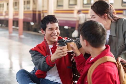 A group of friends joyfully toasting their coffee cups together at a train station, celebrating friendship and connection.
