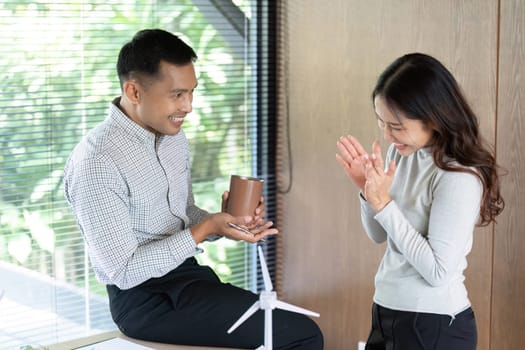 Two colleagues engage in a friendly conversation, showcasing a positive work relationship in a bright office.