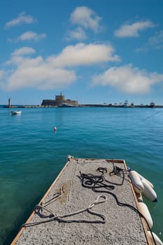 Serene and expansive seascape in Rhodes, featuring the impressive fort and the vibrant blue Aegean Sea under a cloudy sky.