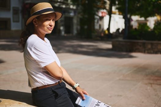 A serene image of a woman in a white shirt and hat sitting outdoors in a sunny park, enjoying the day. The setting features natural light and provides a tranquil, peaceful vibe.