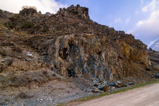 Majestic sedimentary rock formation towers above serene mountainous landscape. Natural beauty creates a rugged and dramatic atmosphere during daytime with clear skies.