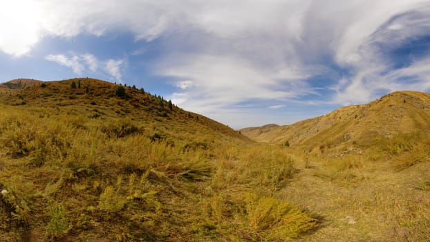 dry yellow grass covered foothills at sunny autumnal day, wide angle view