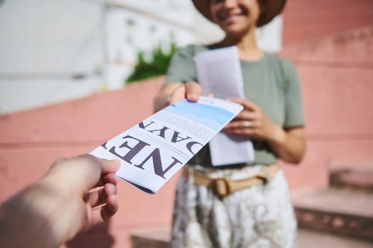 Person in a public setting handing out informational flyers to another, promoting connection, communication, and community engagement.