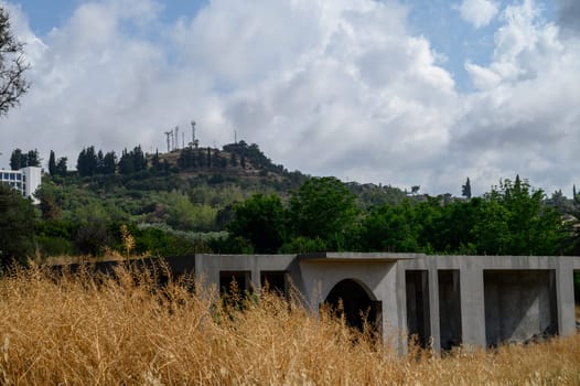An unfinished residential building stands against a mountainous backdrop featuring the iconic Ataturk silhouette, a symbol seen across Northern Cyprus.