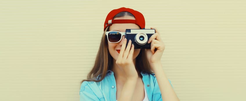 Portrait of happy young woman photographer with film camera, modern girl taking a picture standing on white background