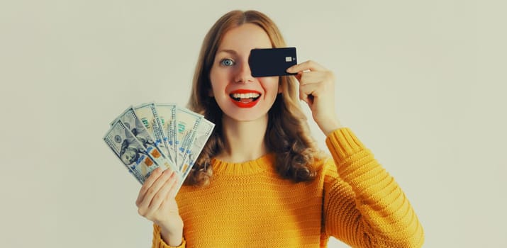 Portrait of happy smiling young woman holding plastic credit bank card and cash money in dollar bills