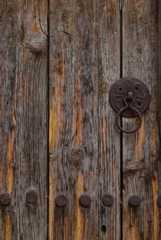 Close-up view of an old wooden door with a vintage iron handle, showcasing traditional craftsmanship and weathered textures in Cyprus.