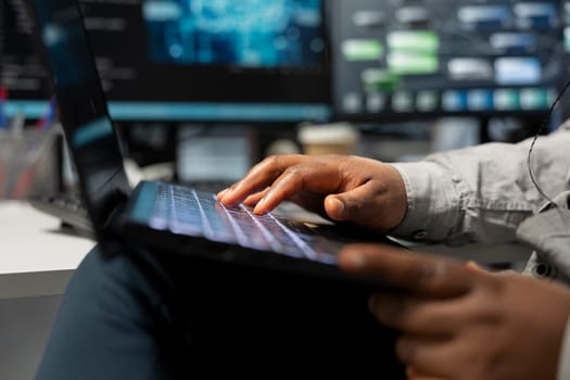 Close up of data center technician using artificial intelligence computerized model on laptop. Server room employee typing on notebook keyboard, using machine learning AI algorithms