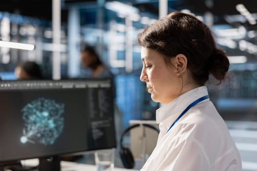 Data center computer scientist analyzing software logs metrics on PC monitor, optimizing systems. Close up of woman in server farm inspecting resource utilization, managing application efficiency