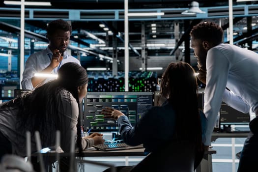Data center programmers doing brainstorming, setting up machine learning systems handling information. Teamworking colleagues training neural networks to improve server farm operations