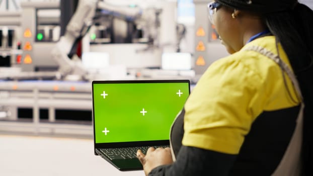 Engineer in photovoltaics factory using chroma key laptop to look at system performance metrics. Worker in industry 4.0 plant using green screen mockup notebook to track energy production, camera B