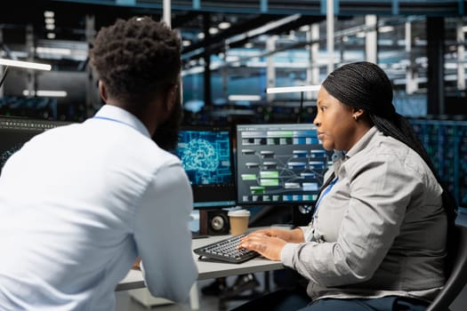 Data center engineering team using artificial intelligence neural networks technology. Professional and coworker in server room using AI programming language to configure specialized hardware