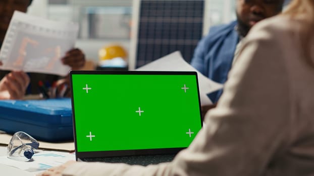 Industrial plant researchers work on breakthroughs in durability and performance using mockup notebook. Factory scientists use green screen laptop to test materials for next generation solar panels