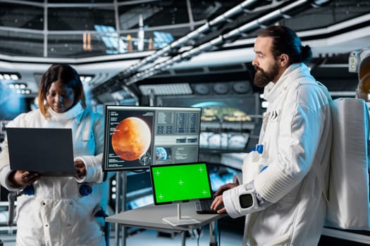 Astronaut checks green screen tablet interface before landing spaceship on Mars. Crew members looking at chroma key device during mission to red planet surface, testing human survival in deep space