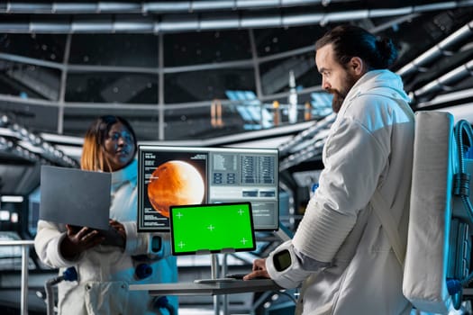 Space station researchers analyzing Mars planetary data using isolated screen tablet. Team of scientists in futuristic spaceship doing Martian surface research using mockup device