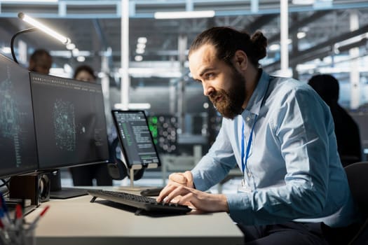 Software developer coding on computer, upgrading artificial intelligence server cabinets doing data intensive operations. IT specialist typing on PC keyboard, updating supercomputers systems