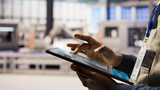 Close up of engineer using tablet to design solar panels factory layouts, utilizing CAD software and simulation tools, optimizing production systems in automated photovoltaics plant, camera A