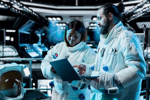 Team of cosmonauts running telemetry software on laptop, preparing for planetary mission outside. Astronauts checking thrusters diagnostics using notebook, beginning landing procedures on planet