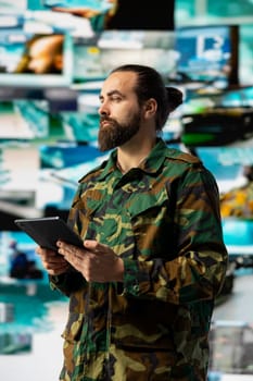 Young veteran reviewing battlefield data in a high tech command center, ensuring war planning through tactics and geopolitics details. Modern military environment focused on protection.