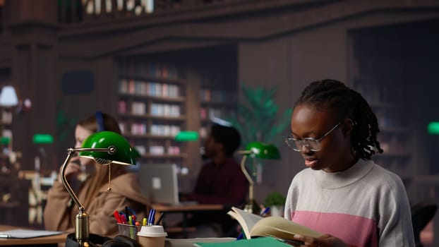 African american girl does bachelor paper research for citations and other information, using the database at the campus library. Intelligent student working on her diploma. Camera A.