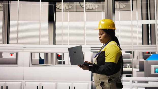 Specialist using laptop to conduct routine inspections in industry 4.0 plant producing renewable energy. Technician in photovoltaics smart factory testing equipment using notebook, camera A