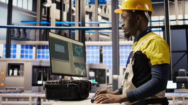 Solar panels plant engineer uses PC to oversee systems, ensuring machinery operates at optimal efficiency. Photovoltaics plant worker uses computer software to maintain continuous operations, camera A