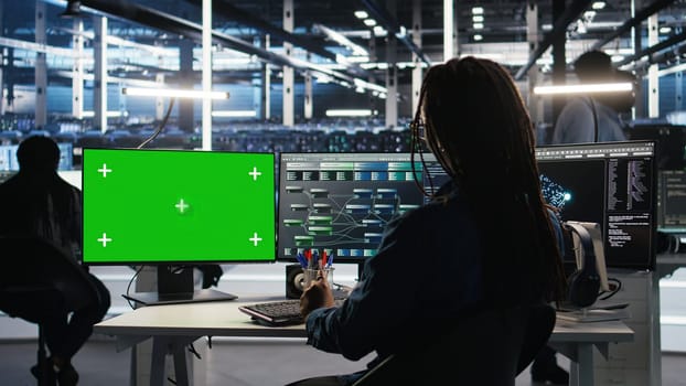 Data center technician using node tree software on green screen PC to analyze datasets. Server room worker using visual programming tools on chroma key computer to improve gear performance, camera A
