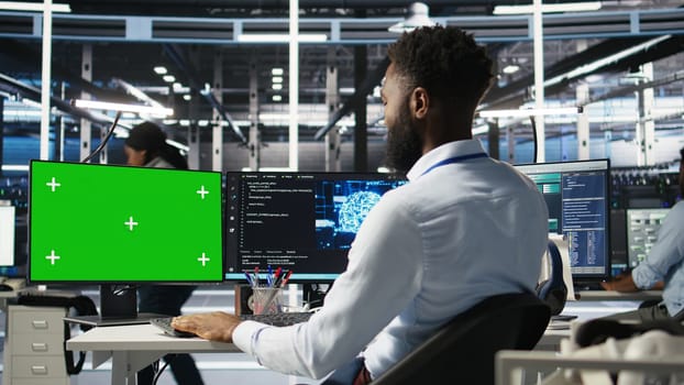 Data center admin using green screen PC to do node tree programming, optimizing resource allocation. Man in server room uses mockup computer predictive AI visualization systems, camera A