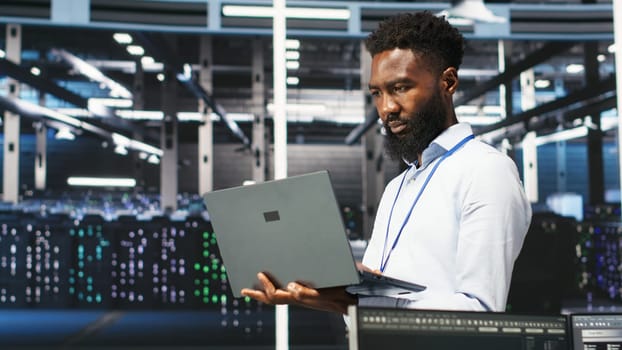 Data center programmer uses node tree software to identify equipment performance issues. African american server farm worker reviews data analysis graph to minimize hardware failures, camera B