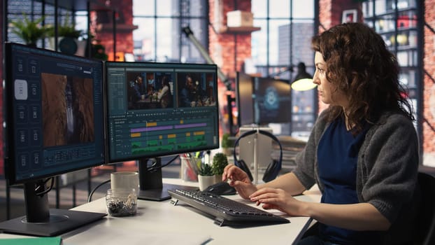 Female videographer working with dual monitors at the creative agency, editing video montage and does color grading for the creative process. Post production to create footage. Camera A.