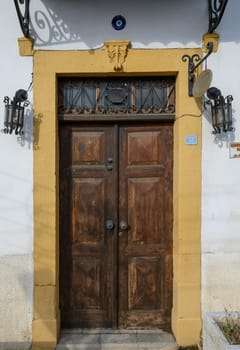 Authentic entrance to a Cypriot home with aged wooden double doors and two classic lanterns on each side, reflecting Mediterranean architecture.