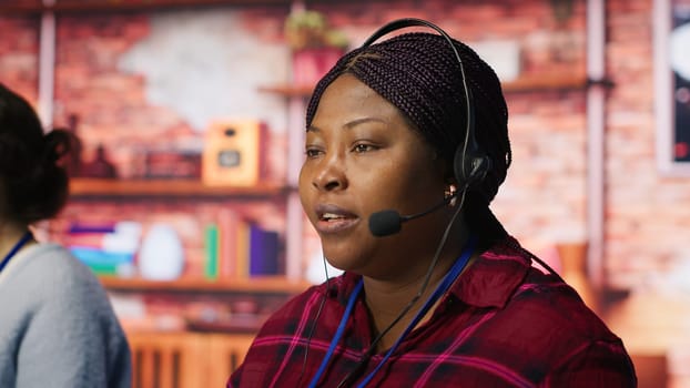 Happy call center agent providing step by step guidance to customers. Smiling customer center worker at PC desk walking clients through technical solutions during call, camera A