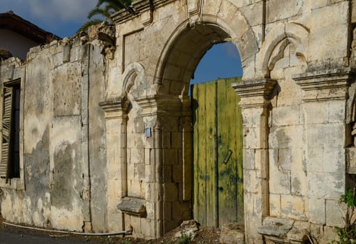 Traditional Cypriot house wall made of stone, featuring aged wooden doors that reflect the rustic Mediterranean style.