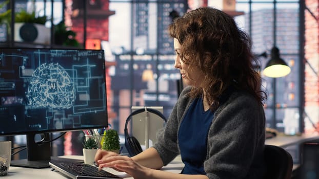 Female system admin doing maintenance on AI brain pc systems, sitting at office desk. Girl works as a software developer with cybernetics and algorithms for machine learning. Camera B.