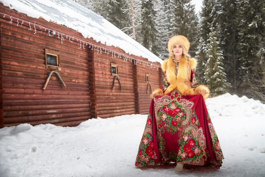 Celebrating Maslenitsa, a girl in a national dress poses with a horse in a snowy landscape surrounded by rustic cabins.
