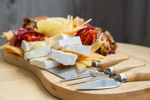 Cheese and meat charcuterie board. Gift present idea, dinner lunch plate. Minimal effort visually pleasing snacks. Simple meal preparation with special cheese knives. Wooden board