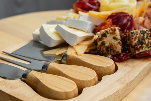 Food trend gift aperitivo party idea. Appetizers wooden grazing board with different antipasti charcuterie snacks and cheese. Assorted cheese meat platter. Disordered eating. Girl dinner