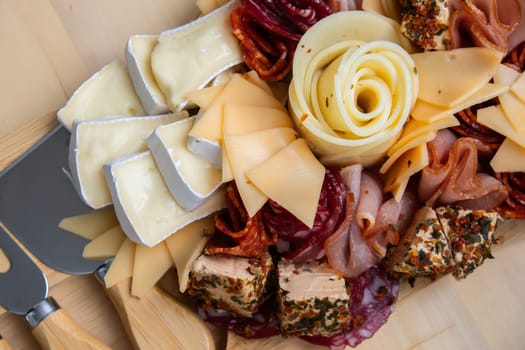 Wooden charcuterie cheese board holiday present idea. Snack starter plate for dinner with wine. Italian appetizers or antipasto set with gourmet food. Buffet party concept