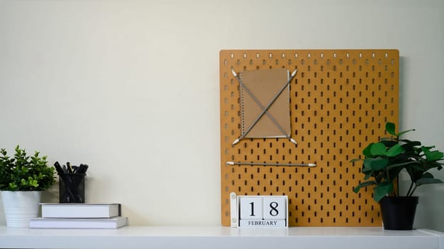 Creative home office decor with a pegboard, notebook, potted plants, and a calendar.