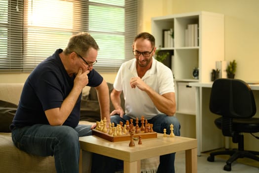 Father and son enjoying a strategic game of chess together in a cozy living room. Father day concept.