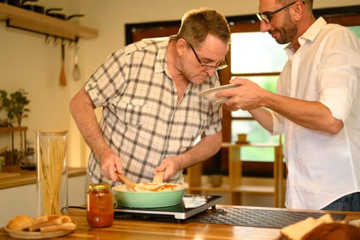 Father and son enjoy cooking a fresh homemade dish in a home kitchen. Father day concept.