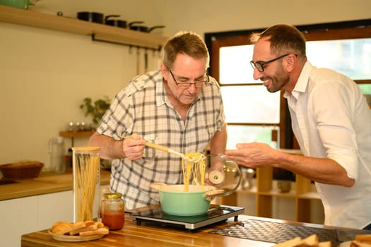 Father and son enjoy cooking a fresh homemade dish in a home kitchen. Father day concept.