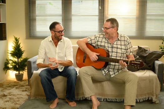 Father and adult son bonding over music, enjoying quality time with acoustic guitar. Father day concept.