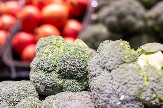 A sizable bunch of fresh broccoli is stacked neatly on top of each other in a grocery store, ready for customers to choose from