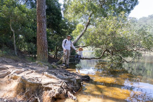 Father and son enjoying a sunny day by the lake, exploring nature and creating memories together